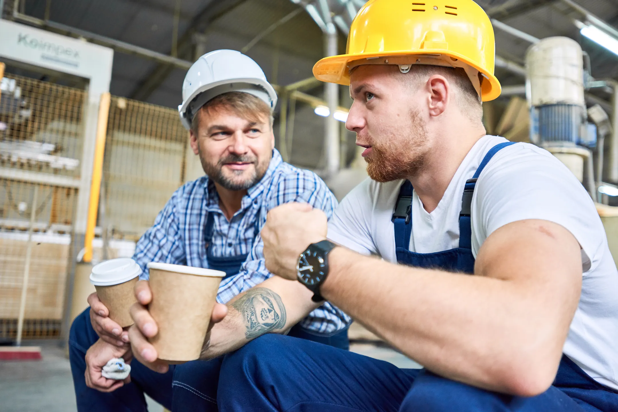 two factory workers taking a break and drinking coffee together